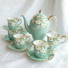 a tea set with four cups and saucers in the shape of flowers on them