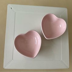 two pink heart shaped bowls sitting on top of a white tray