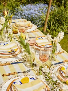 a table set with plates, glasses and napkins for an outdoor dinner party in the garden