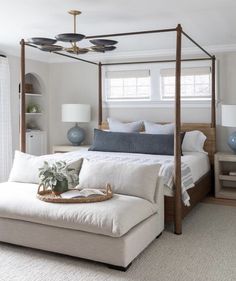 a bedroom with a four poster bed and white linens on the floor, along with blue vases