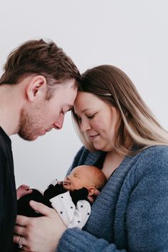 a man and woman holding a baby in their arms