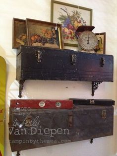 an old trunk is sitting on top of a shelf next to other antiques and framed pictures