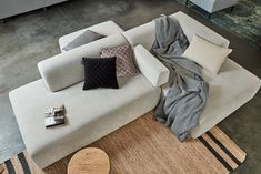 a couch with pillows and blankets on top of it next to a coffee table in a living room