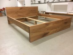 a bed frame made out of wood in a room with white walls and flooring