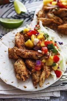 two tacos with chicken, pineapple salsa and avocado wedges on the side