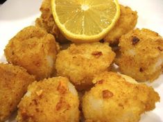 fried scallops with lemon wedges on a white plate