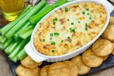 a plate with crackers, celery and dip