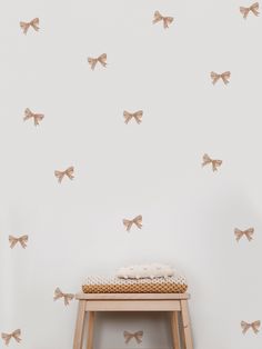 a small stool in front of a white wall with bows on it and a wooden bench underneath