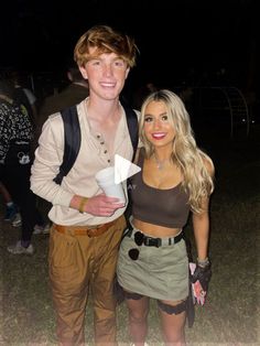 a man standing next to a woman on top of a grass covered field at night