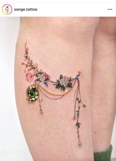 a woman's thigh with flowers and jewels on it