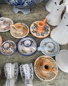 there are many plates and cups on the counter top, including one with an orange handle