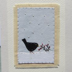 a black bird is standing in the snow with berries on it's nose and beak