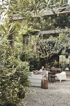 a man sitting on top of a white couch in a garden