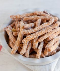 a white bowl filled with sugary pretzels on top of a table