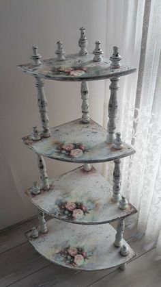 three tiered display case with flowers painted on the bottom and sides, sitting in front of a window