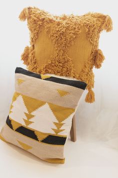 a yellow pillow sitting on top of a wooden chair next to a brown and white pillow