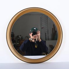 a man is taking a photo in the mirror with his cell phone while wearing a baseball cap