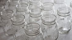 many empty mason jars lined up on a tableclothed surface with the lids down