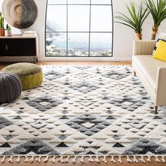 a living room with a large window and white rugs on the hardwood flooring