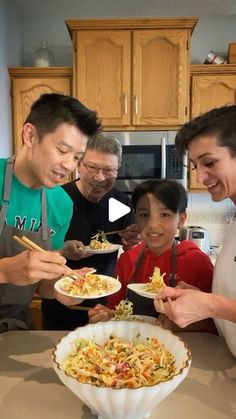 a group of people standing around a table with plates of food in front of them