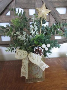 Vintage gold metal mesh "bag" holds floral foam covered with festive paper and filled with frosted faux eucalyptus sprigs and other greens.  We've added a snowy pinecone, some white beaded berries, a glittery metal star and a gold and cream wired bow printed with "JOY".  This sweet arrangement would look great on a mantle or side table, attached to a larger wreath, or using the handle of the bag, hung on an interior door for a festive touch.  OOAK - one of a kind, for sure.   Measures about 15" Beaded Berries, Snowy Pinecone, Wreath Door Hanger, Faux Eucalyptus, Metal Star, Large Wreath, Wreath Door, Christmas Arrangements, Metal Stars