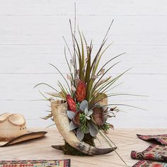 a vase filled with flowers on top of a table next to a cowboy's hat