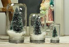 three snow globes sitting on top of a table next to a christmas tree in a glass jar