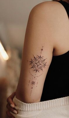 a woman's arm with a tattoo on it that has stars and circles in the middle