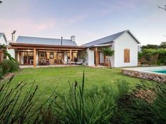 a house with a pool in front of it and grass around the back yard area