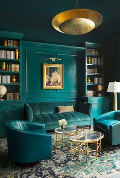 a living room with green walls and blue couches in the corner, gold accents