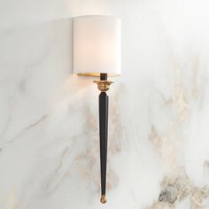 a wall light with a white shade on it's side against a marble background