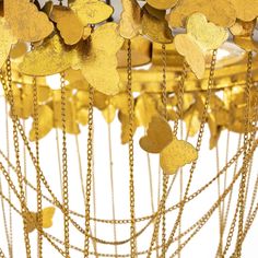 a bunch of gold hearts hanging from a ceiling fixture with chains attached to the sides