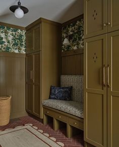 a room with wooden cabinets and a bench in the corner, along with a rug on the floor