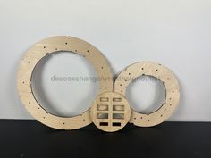 two circular wooden frames sitting on top of a black table with holes cut out into them