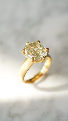 a yellow diamond ring sitting on top of a white table