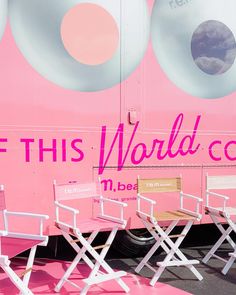 there are three chairs sitting in front of a pink bus that says, if this world comes