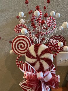 candy canes and lollipops are arranged in a vase on the wall