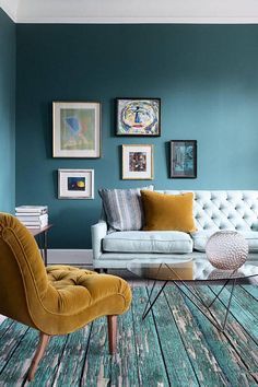 a living room with blue walls and pictures on the wall, two yellow chairs in front of a white couch