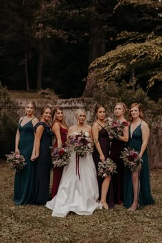 a group of women standing next to each other in front of some trees and grass