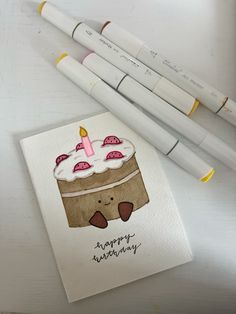 three markers are next to a card with a birthday cake on it