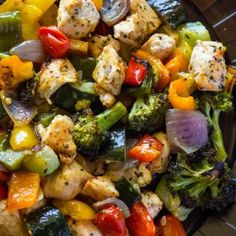 a salad with chicken, broccoli, peppers and onions in a black bowl