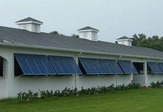 a white building with blue solar panels on the roof and windows in front of it