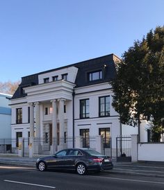 a black car parked in front of a large white building