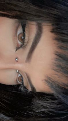 a woman with black hair and piercings on her nose