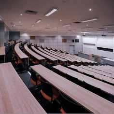 an empty lecture hall with wooden tables and chairs