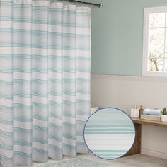 a blue and white striped shower curtain in a bathroom with a rug on the floor