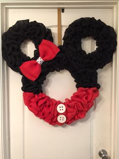 a mickey mouse wreath is hanging on the front door with two buttons attached to it