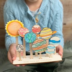 a young child is holding an assortment of solar system magnets in front of her