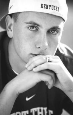 a black and white photo of a young man wearing a hat with the word kentucky on it