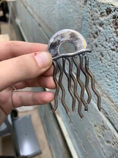 a hand holding a piece of metal that looks like a jellyfish